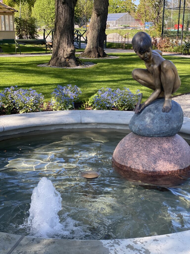 Staty en liten flicka på en sten vid en fontän